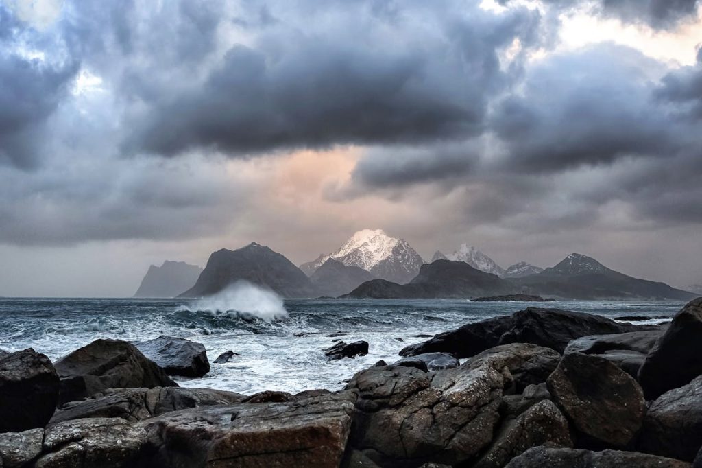 Waves Crashing on Rock Near Mountains during Datyime